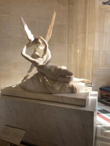 Image of the statue Psyche Revived by Cupid's Kiss, lit up by golden light coming through the window.