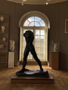 Inside Musée Rodin, an image of a sculpture of a man in front of a window.