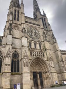 Image of the front of St. Andre Cathedral in Bordeaux. There are two towers and a grand doorway with gothic architecture. 
