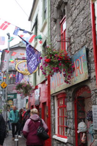 Street of Galway. Features a sign for a local store and many flags.