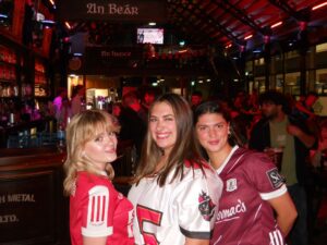 Three girls in sports jerseys smiling at the camera.