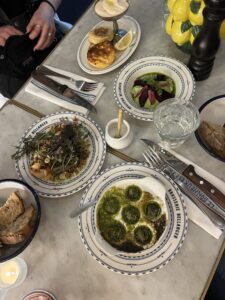 Multiple plates of appetizers, such as escargot.