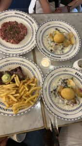 Dinner plates including steak frites, steak tartar, and veggie dishes