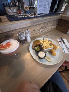 A plate of fish and chips and a pink drink