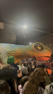 A float decorated as a newt, in a crowd of people