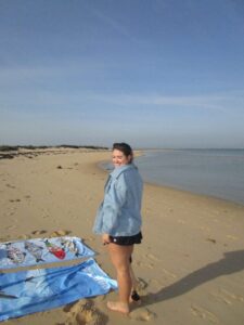 A girl standing and smiling in front of the ocean