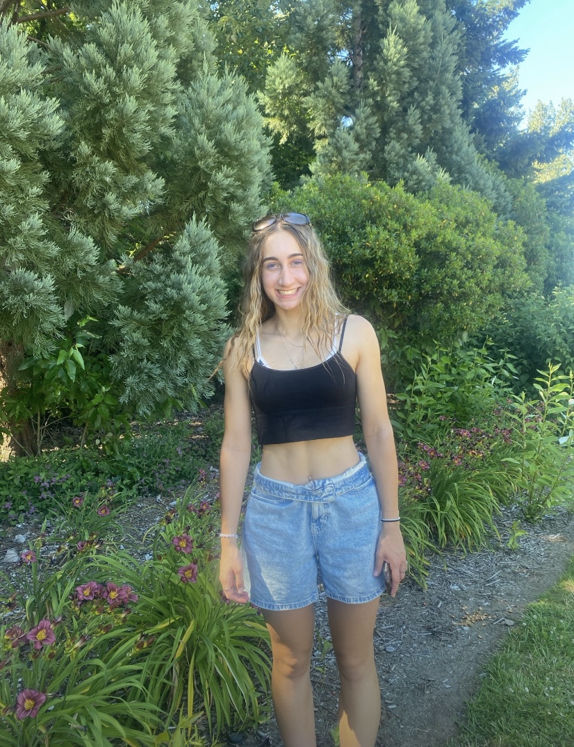 This is a photo of me from this past summer standing outside in front of some trees and flowers at a park called Foothills in Lake Oswego, Oregon