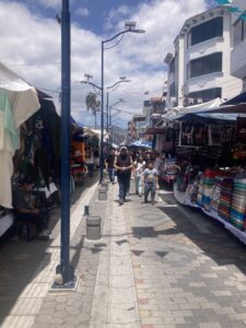 A street in the town of Otavalo in the main square. The path is crowded and lined with many market stalls.