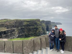 Three people standing and smiling in front of the Cliffs of Moher