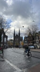 A biker biking in front of a cathedral in Amsterdam.