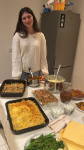 A girl is standing in front of a table full of food