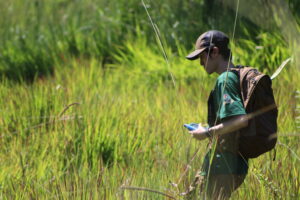 A photo of me walking through a field, holding a GPS unit.