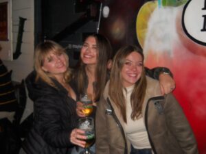 Three girls smiling, holding drinks