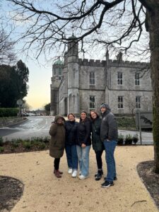 5 people stand in front of an old building