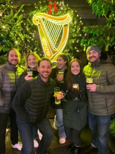 6 people stand in front of a Guinness sign smiling