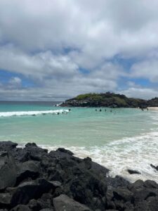 A sandy bay with people surfing.