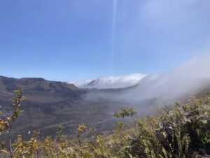 A large volcanic crater with clouds creeping over the rim.