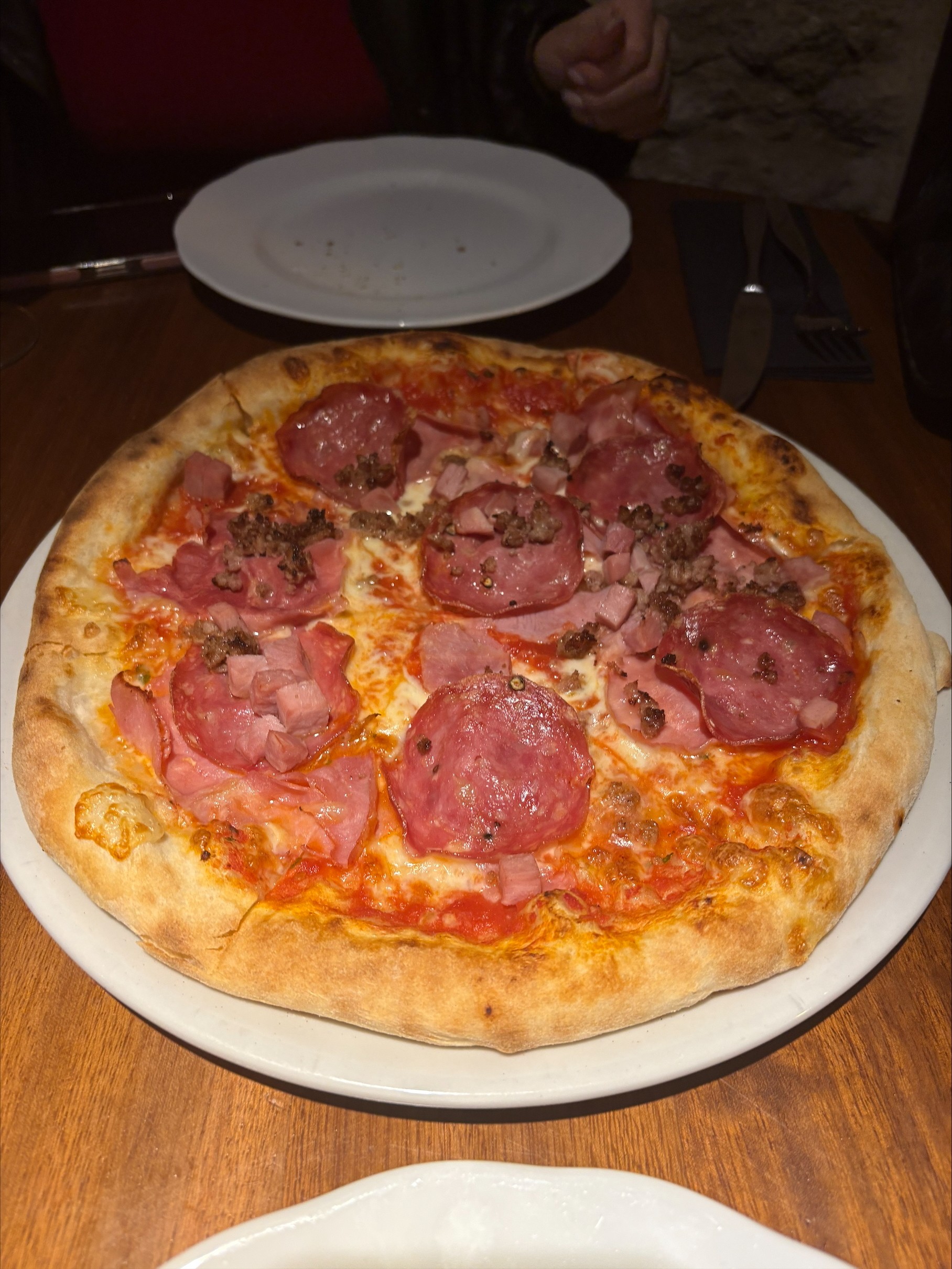 A photo of a pizza from the restaurant Bachio that we tried, it is a meat pizza with ham, salami, and ground sausage