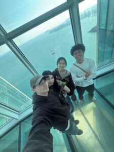 Friends at BUSAN X sky tower overlooking a beautiful ocean.